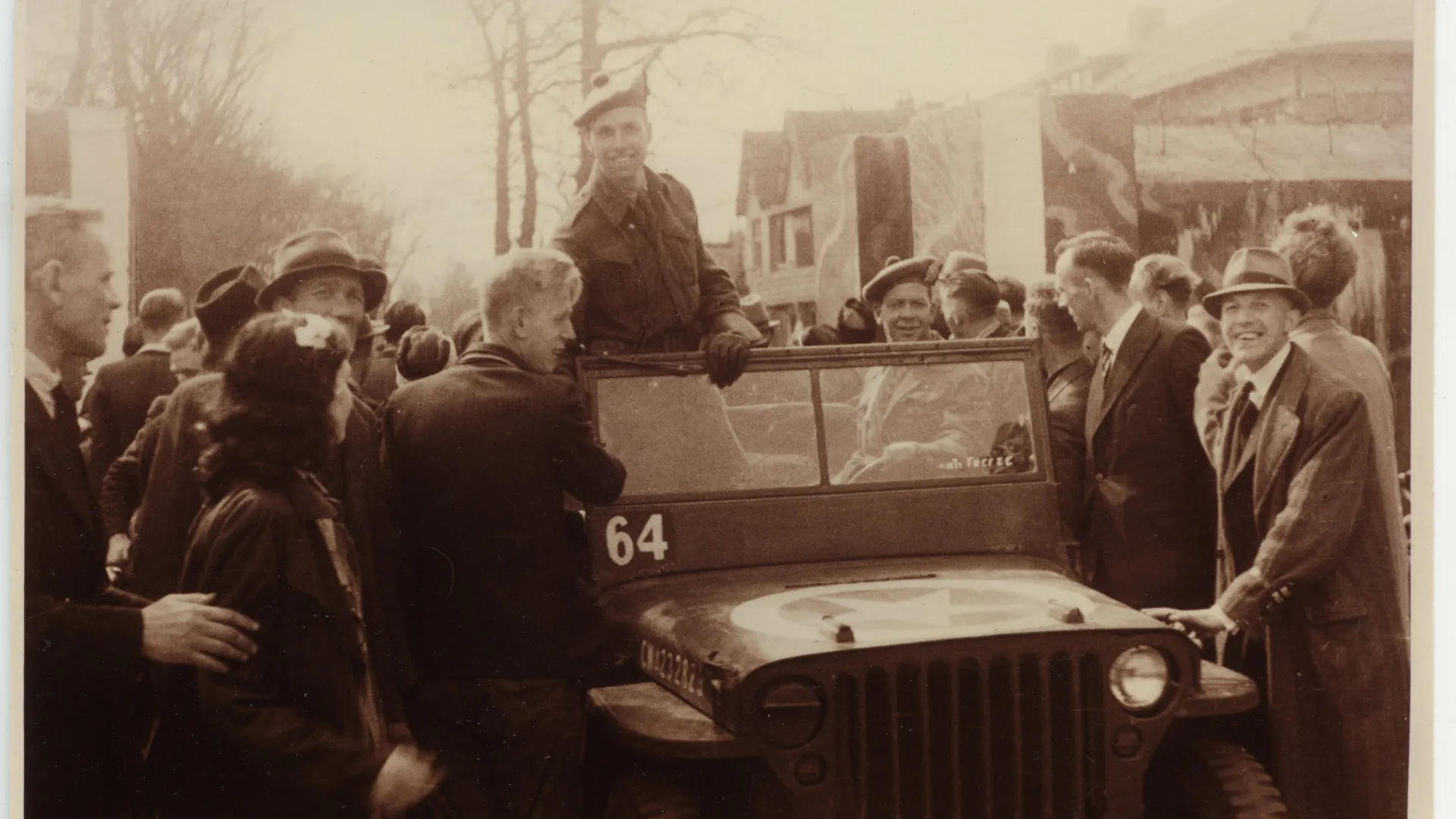 Foto van bevrijding in Drenthe, vrolijke mensen, jeep in het midden met lachende militair